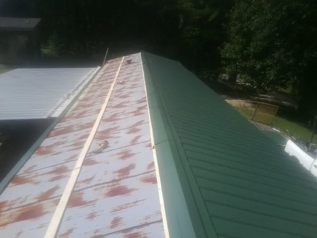 Old rusted panels beside newly installed green metal roofing — Wind Damage Roof Repair by Roofing Brothers in Waldo