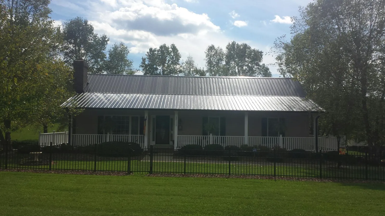 Gray metal roof on a brick ranch with a full width front porch — Gutter Guard Installation work by our crew in Waldo
